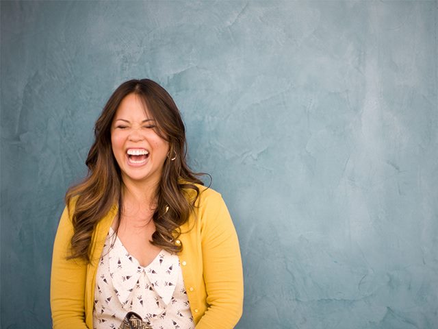 Woman in bright clothes laughing. 