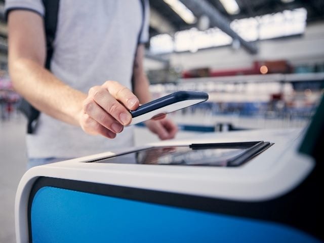  Hand of man during using self service check-in machine at airport terminal. 