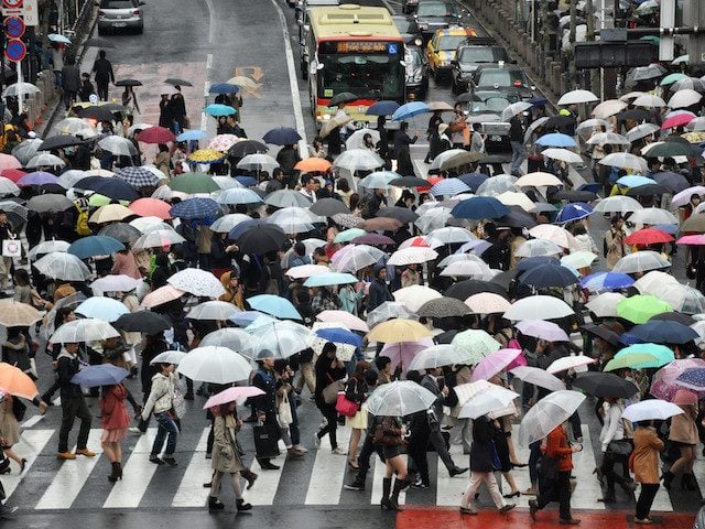 busy intersection filled with people holding umbrellas