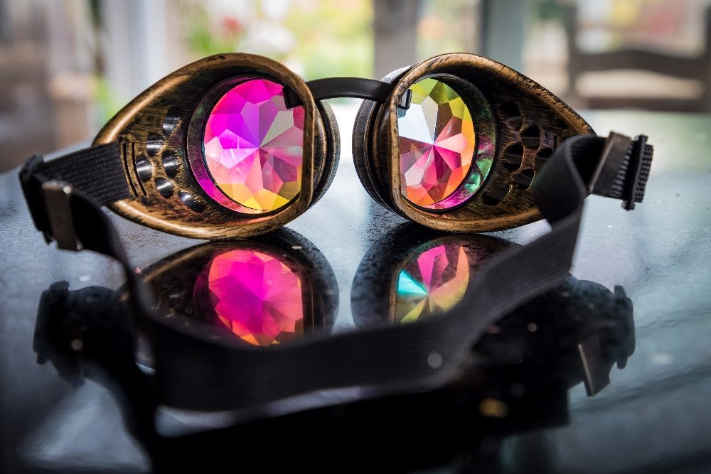 A pair of colorful kaleidoscope goggles sit on top of a shiny black surface in piece about the different aspects of a UX audit.