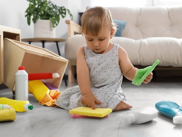 Baby playing with cleaning supplies on floor at home, just like brands need to empower customers with usability testing.