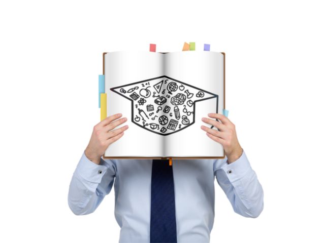 Man holding up a sign over his face with a graduation cap drawn on it - Marketing Certifications concept