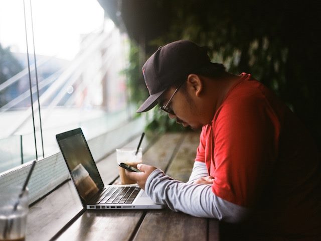 man working in a cafe on phone and laptop