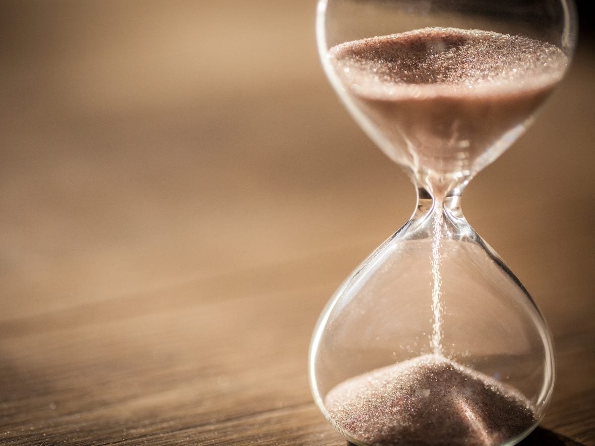 Sand running through the bulbs of an hourglass measuring the passing time in a countdown to a deadline with copy space. 