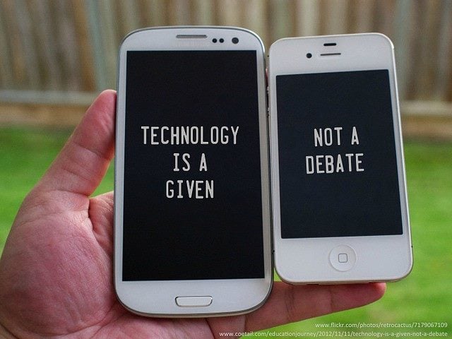 Two iPhones in someone's hand. One of the left says, "Technology is a given" on the screen, the one of the right says, "Not a debate" on the screen