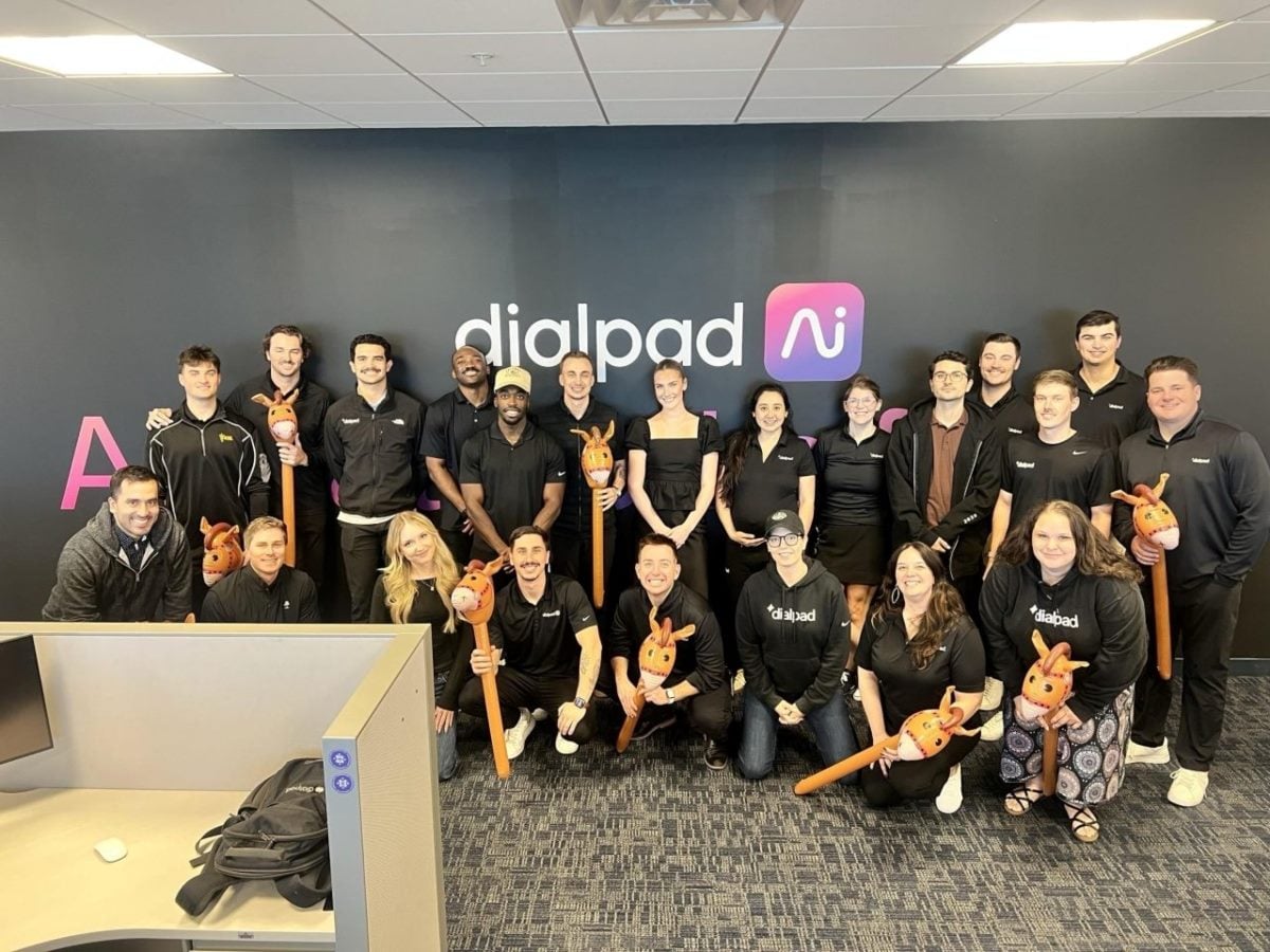 Dozens of people in front of a Dialpad logo inside an office building.