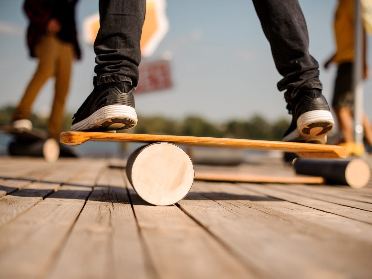 Man standing on the balance board on the wooden pier.