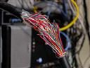 lose-up of a thick cable with dozens of exposed, multicolored wires, symbolizing data fragmentation or disconnected systems in a technology setup.