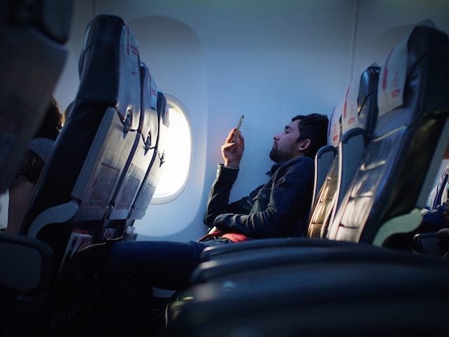 man looking at his phone on a plane