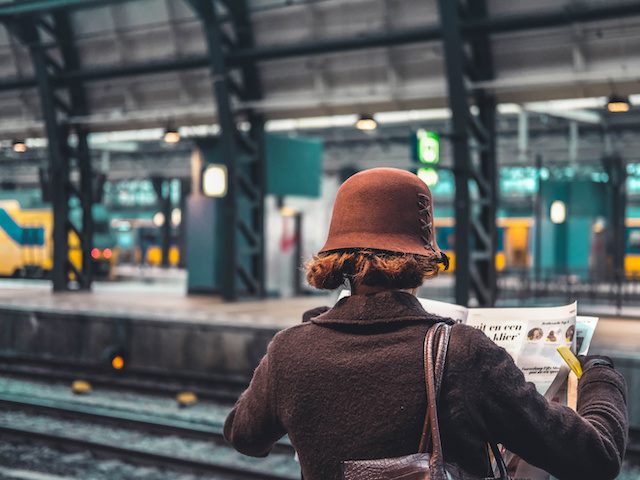 woman reading newspaper on train platform