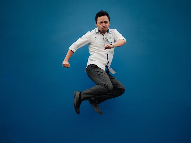 man jumping up in the air against blue background
