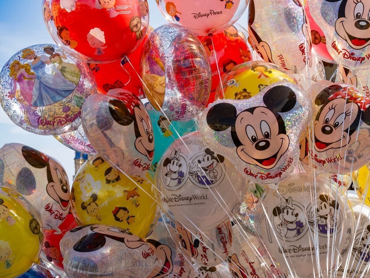 Colorful Mickey Mouse and Disney-themed balloons clustered together, featuring various characters and designs in a bright outdoor setting.