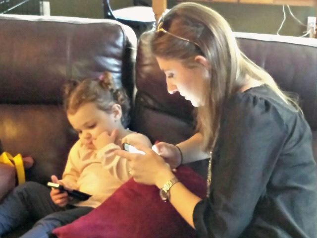 A woman and a baby simultaneously use mobile devices
