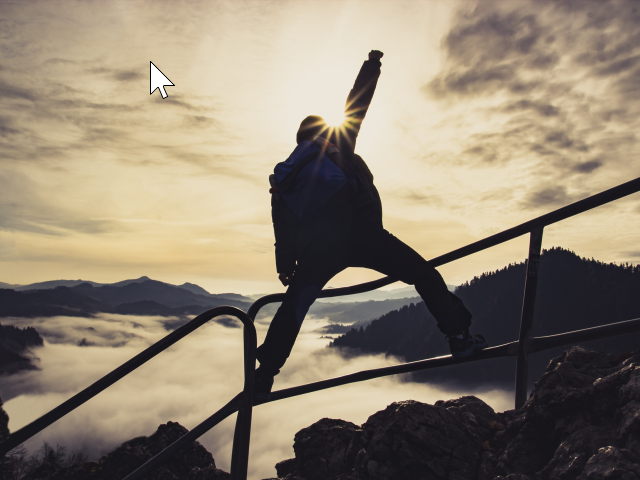 Man with raised hand on top of a mountain, the concept of success, overcoming all challenges and achieving goals
