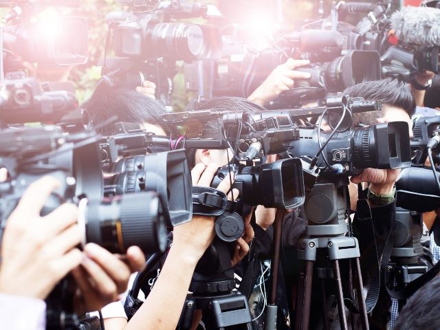 People holding news cameras taking pictures.
