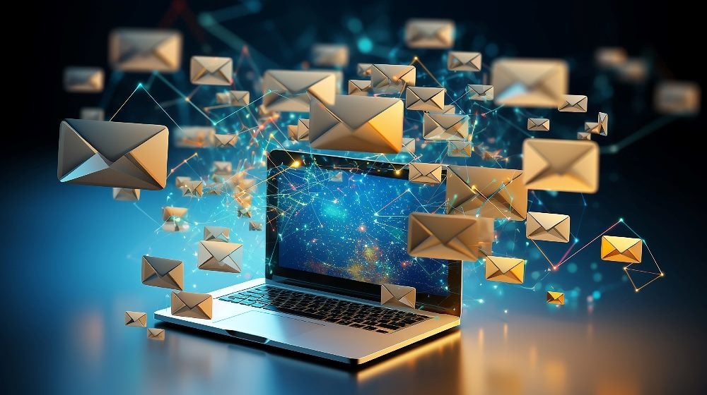 A laptop sits on a table with a blue screen displayed with multiple tan envelopes distributed against a blue background in piece about email marketing stakeholders.