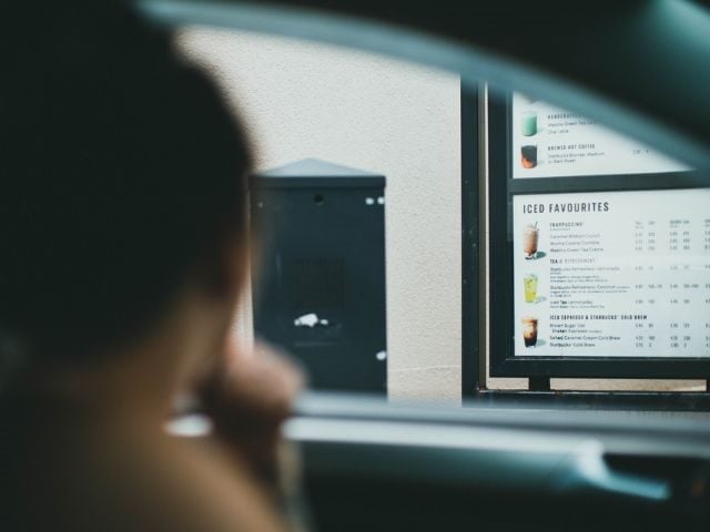 A person in a car sitting at a drive-thru
