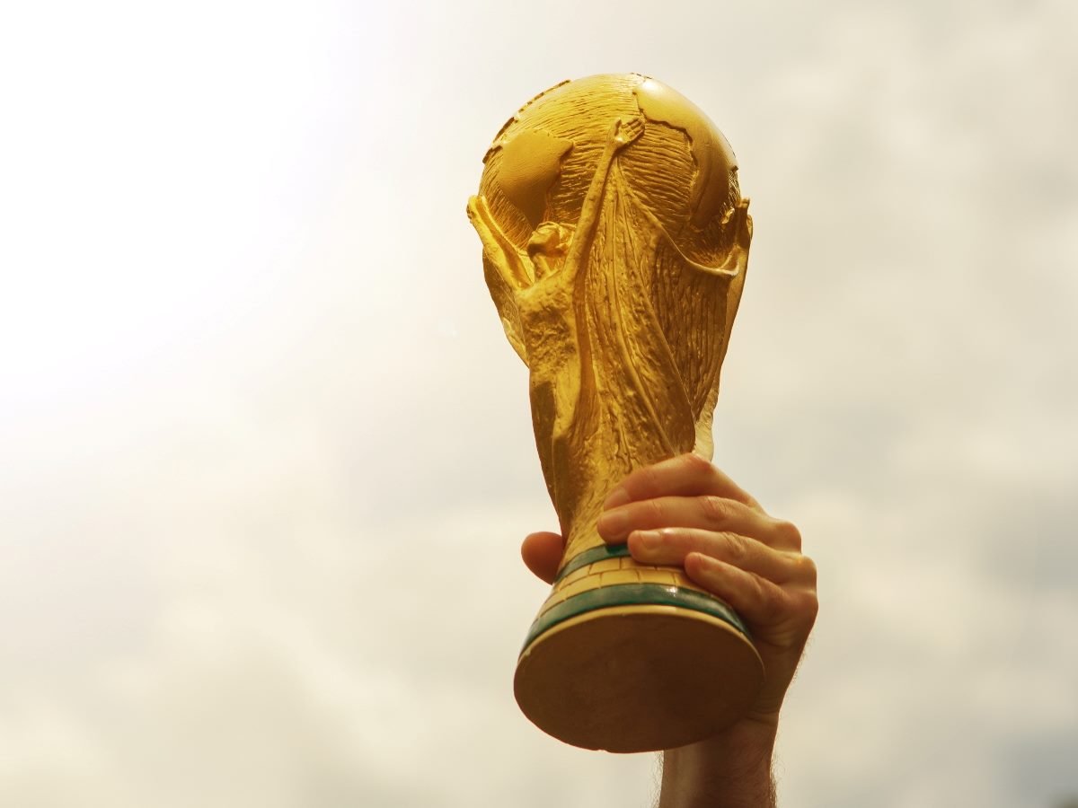 A hand holding up the World Cup soccer trophy.
