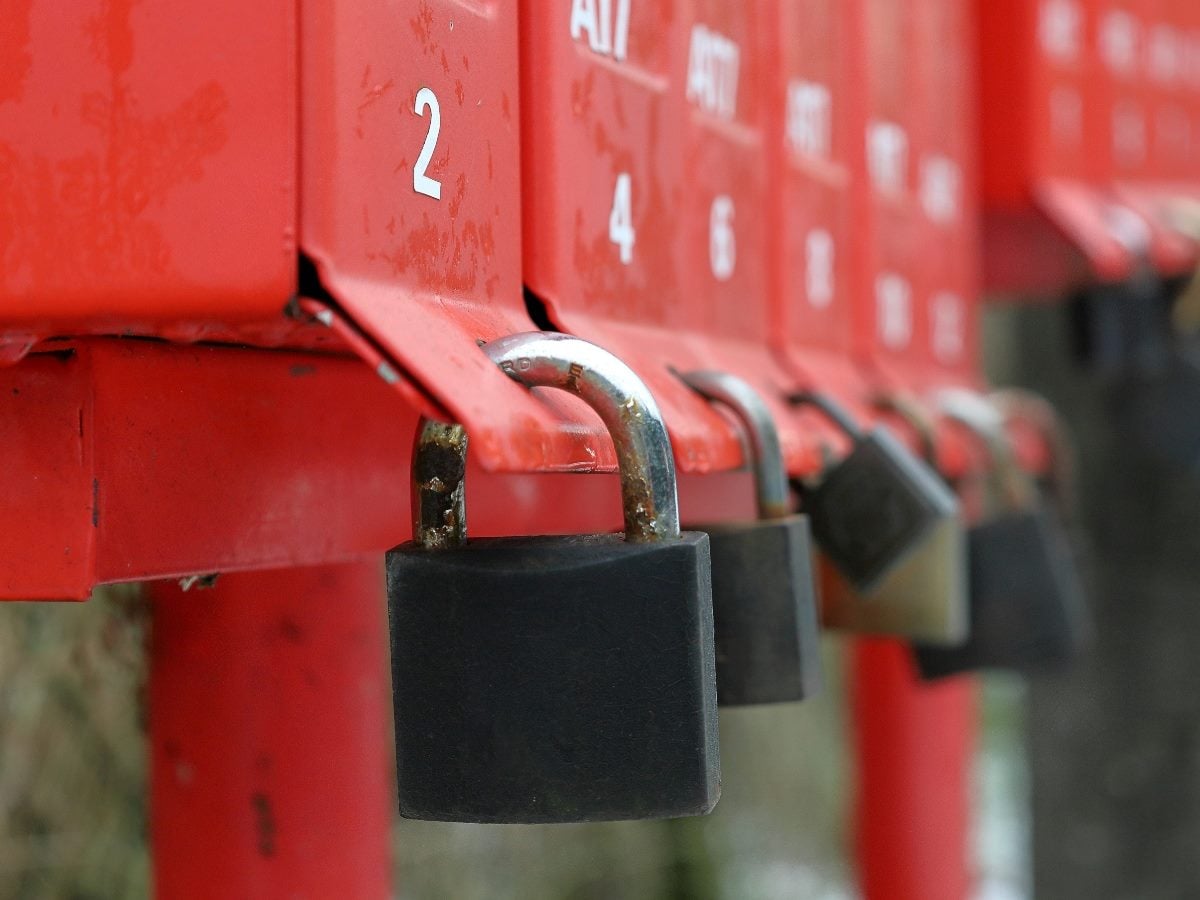 Close-up of red mailboxes with black padlocks secured on each door, symbolizing restricted access or blocked communication.