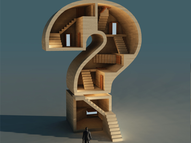A question mark shaped building with an office worker standing in front - Business Question concept