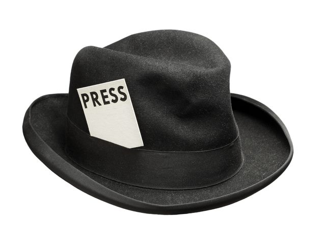 A reporter's black fedora hat with a press card in it.