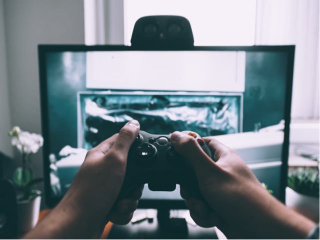 man holding a gaming control device aimed at a screen