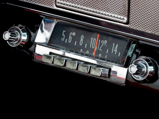 A vintage car radio with silver dials and button sand a red needle with white numbers, suggesting the viability of radio advertising. 