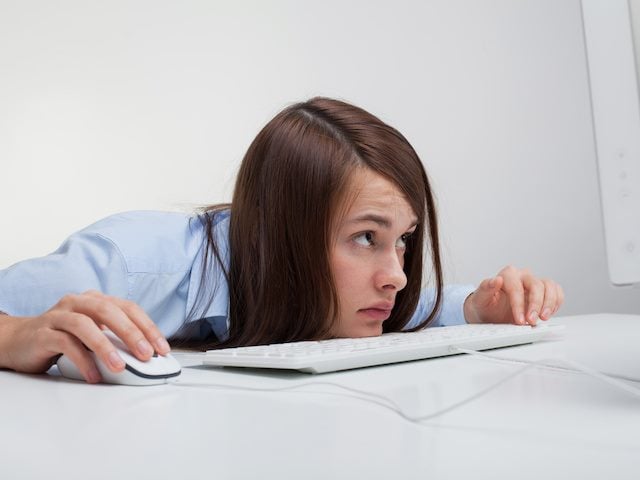 woman looking up at her computer screen with trepidation