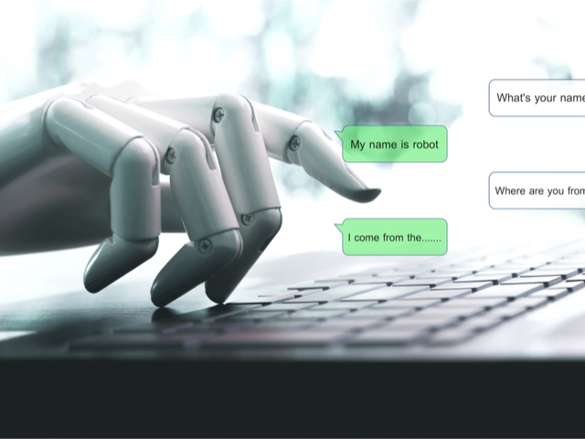 A robot hand initiating conversation through a laptop keyboard - conversational UX concept
