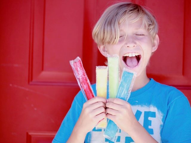 young boy holding a bunch of popsicles