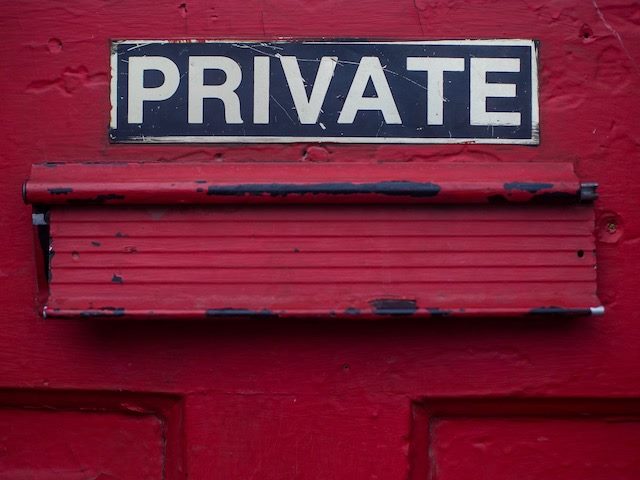 private sign over a letter opening in a red door