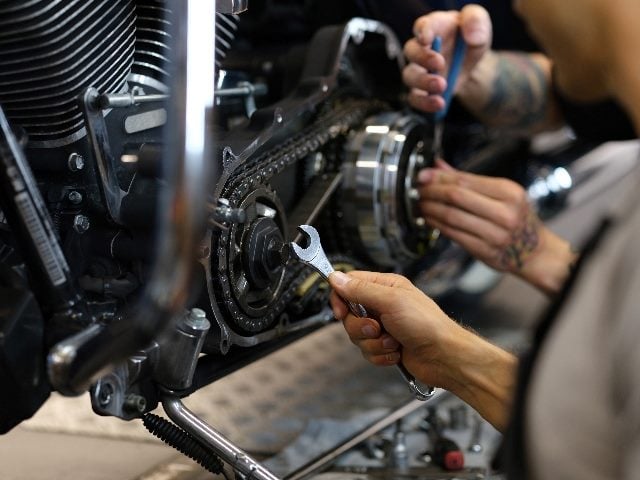  Maintenance of motorcycle engine clutch system by technicians; you can only see the technicians' hands working on the engine. 
