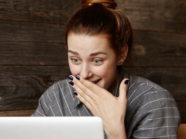 a woman with a surprised face looking at her laptop