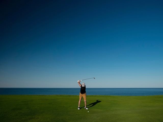 golfer in front of a body of water, getting ready  to hit the ball