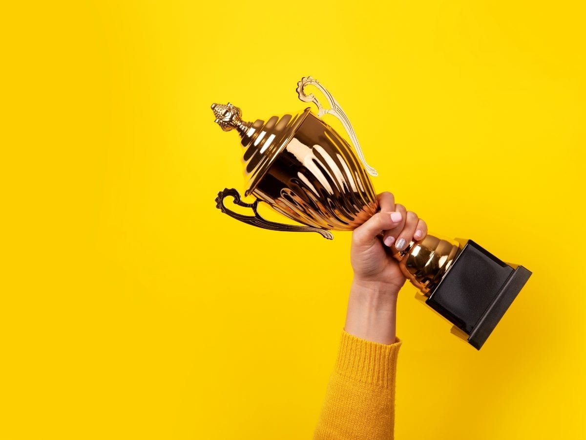 Claude responded: A triumphant arm raised against a bold yellow background, clutching a gleaming gold trophy cup — classic winner energy.A triumphant arm raised against a bold yellow background, clutching a gleaming gold trophy cup — classic winner energy. The matching yellow sleeve is a nice accidental (or very intentional) touch. 
