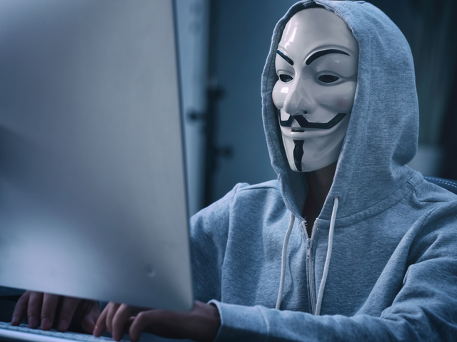 A hacker stealing data from a PC terminal in a server room - IoT security