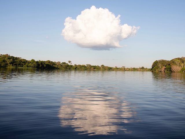 a cloud  over a  lake with a perfect  reflection below