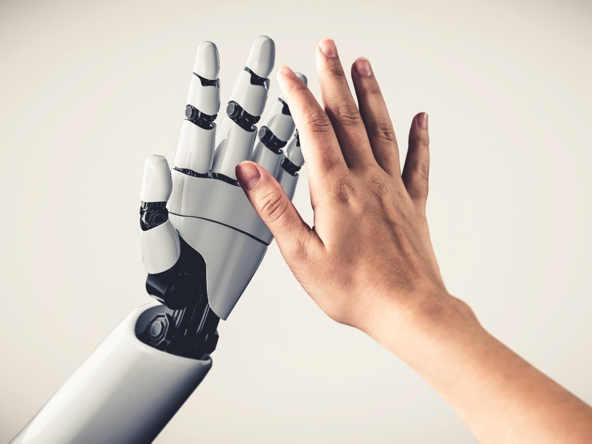 Human hand reaching toward a robotic hand, symbolizing collaboration between people and artificial intelligence.