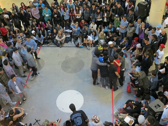 Large group of people gathered around a smaller huddled group.