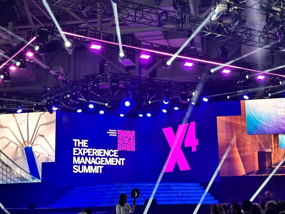 Scene at Salt Palace Convention Center keynote room for the Qualtrics X4 conference. Signage on stage says, "The Experience Management Summit."
