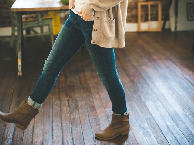woman in brown booties taking a step on a wooden floor
