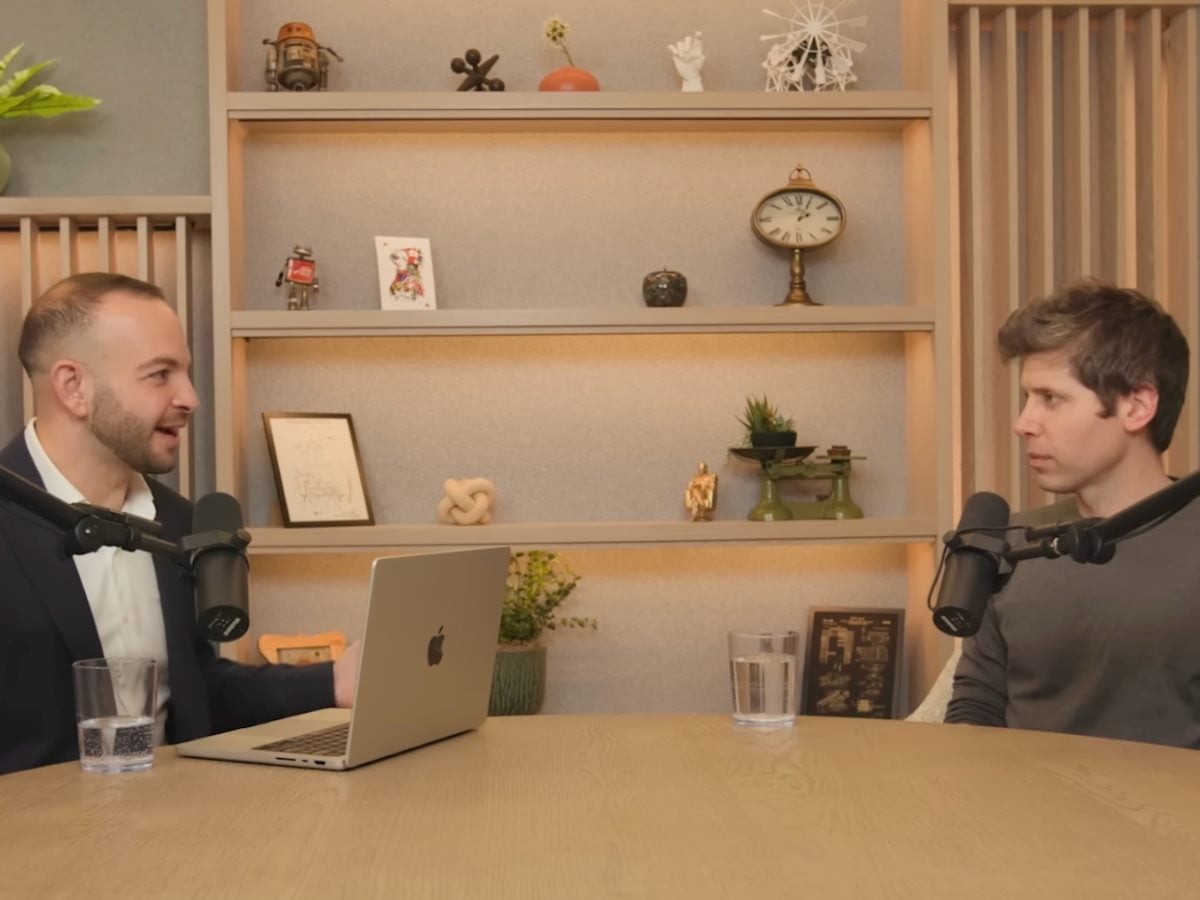 Alex Kantrowitz, left, interviews Sam Altman, as the two sit down with podcast mics.