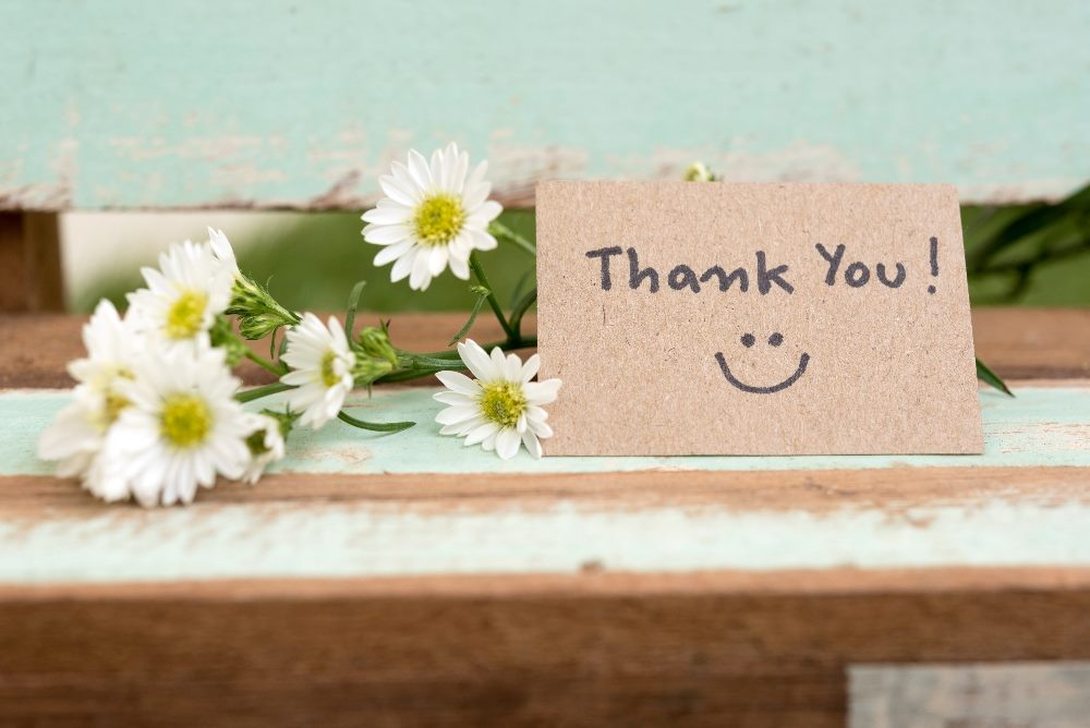 A handwritten thank you note with a cluster of white flowers to the left in piece about building trust with customers.