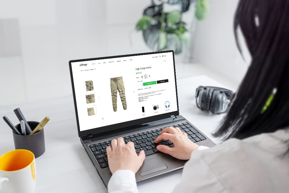 A woman browses online for cargo pants on a laptop in piece about digital commerce strategy.