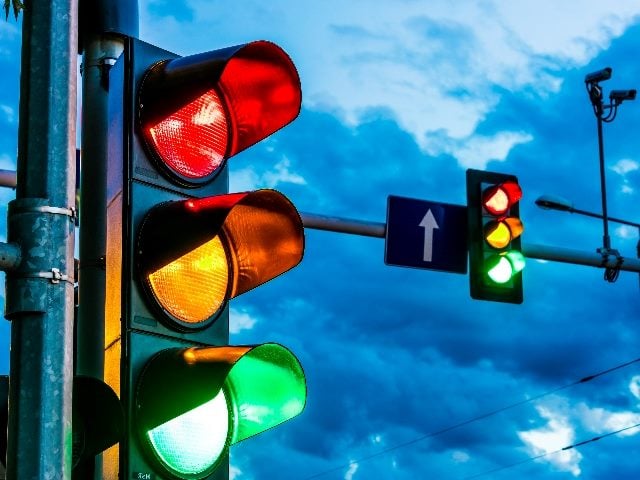 Two traffic lights hang over an urban intersection with a dramatic dark sky in the background symbolizing he needs for Generative AI Safeguards. 