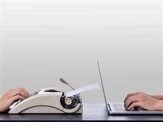 Typewriter vs laptop on a desk with a white wall background - Old vs New Concept