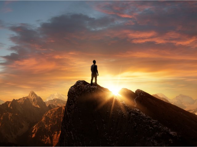 A businessman standing at the top of the mountain enjoying the view 