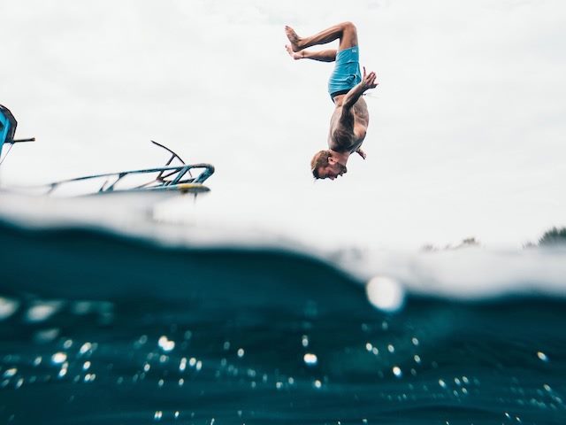 man doing a backflip into the water
