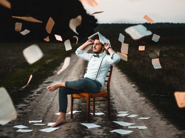 man sitting around with papers flying around him