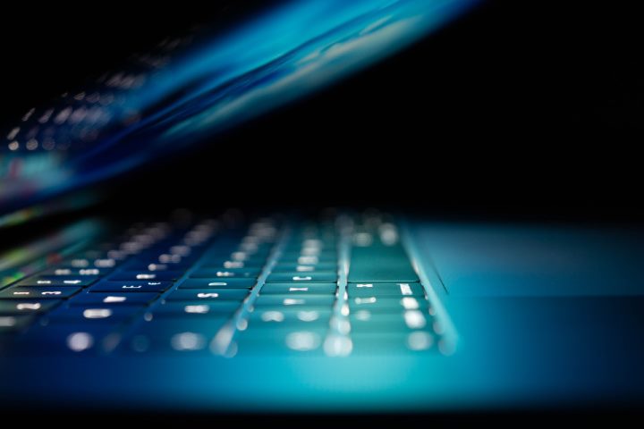 partially open laptop computer with keyboard and screen illuminated